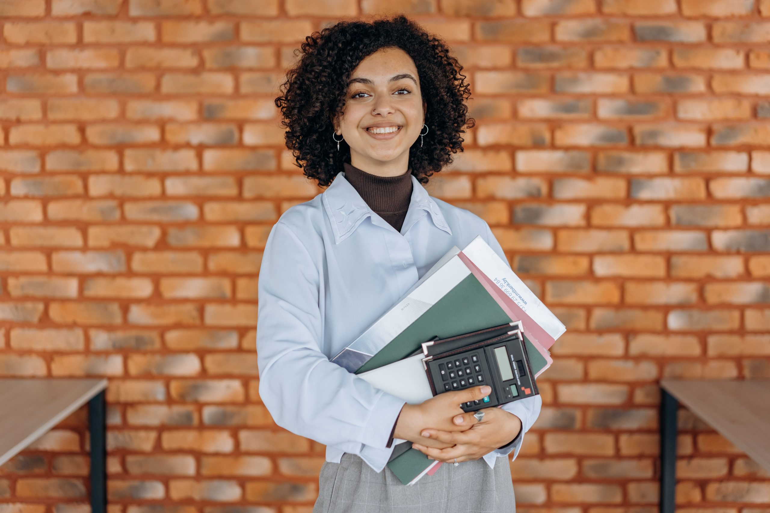 Female student holding books and calculator while standing outdoors