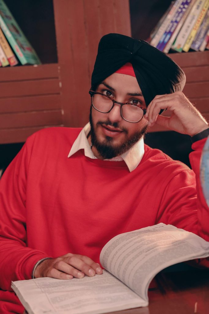 Male student studying with an open book in a library